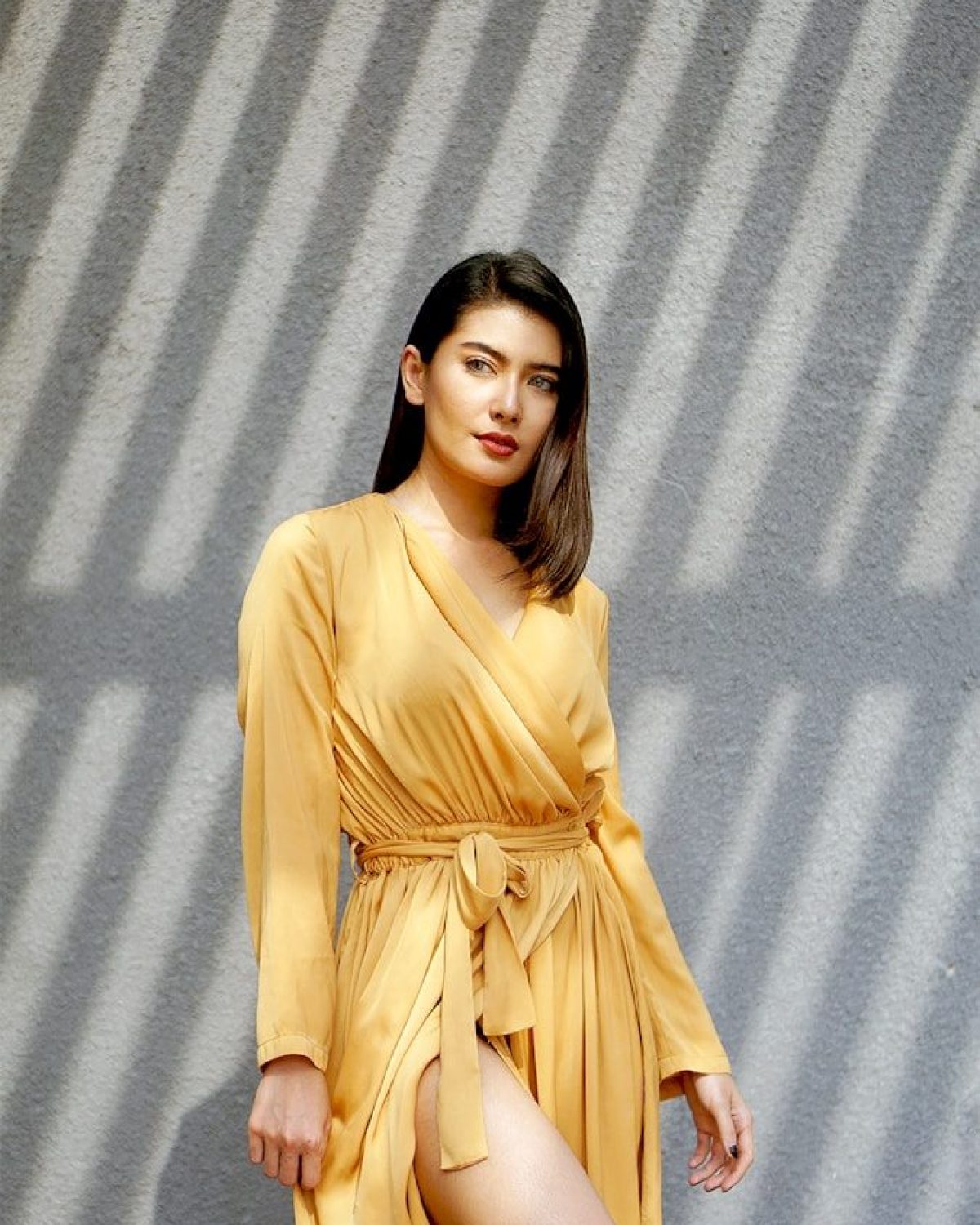 woman in brown long sleeve dress standing beside gray wall