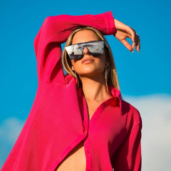 Photo by Jose Mizrahi a woman wearing a red hoodie and sunglasses